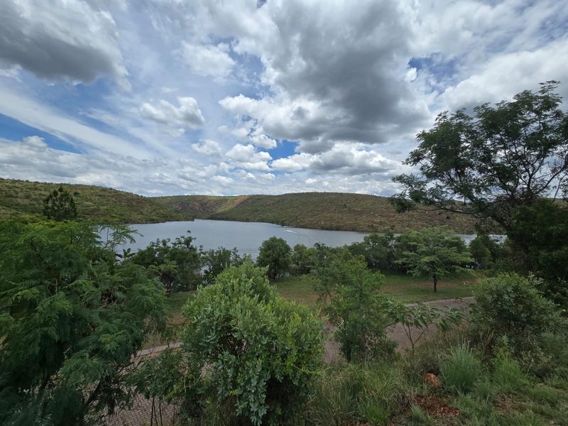 A scenic view of a lake surrounded by rolling hills and natural vegetation, showcasing the tranquil landscape of the property.