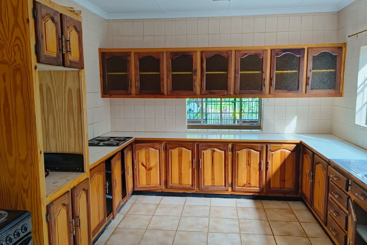 A functional kitchen featuring extensive wooden cabinetry, tiled backsplash, and built-in hob, offering a classic layout ready for modern updates.