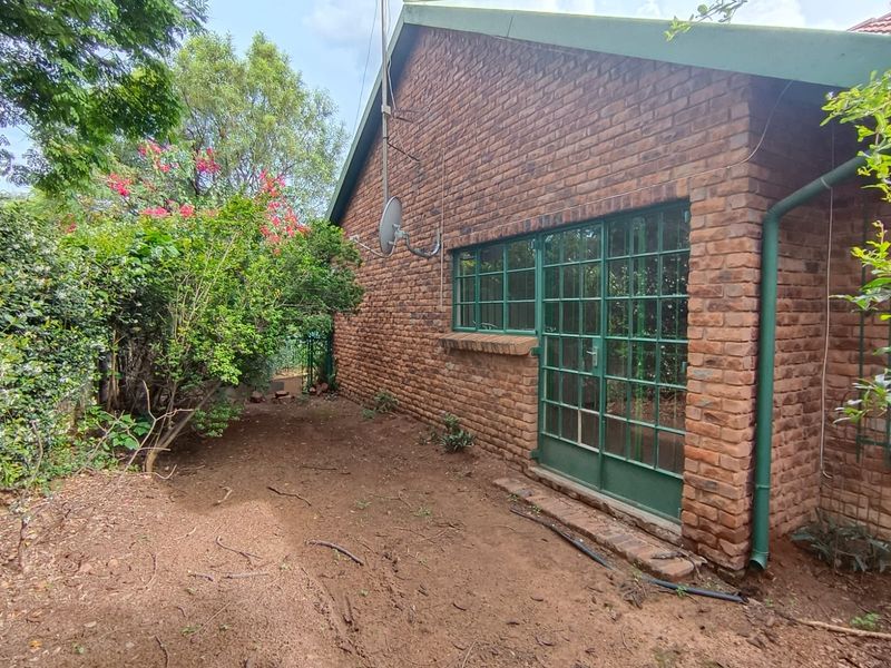 Rear view of the property featuring a face brick facade, steel-framed windows and door, and an adjacent garden area.