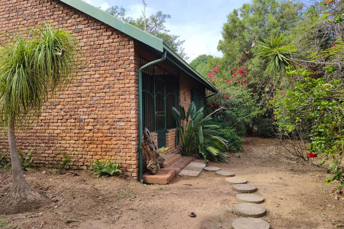A view of the rear exterior featuring a face brick facade, metal security gate, and a garden path leading to the entrance.