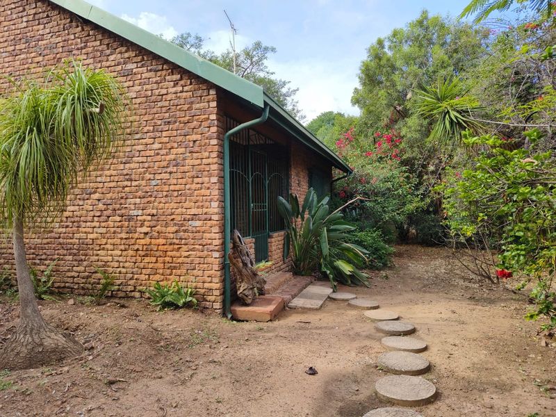 A view of the rear exterior featuring a face brick facade, metal security gate, and a garden path leading to the entrance.