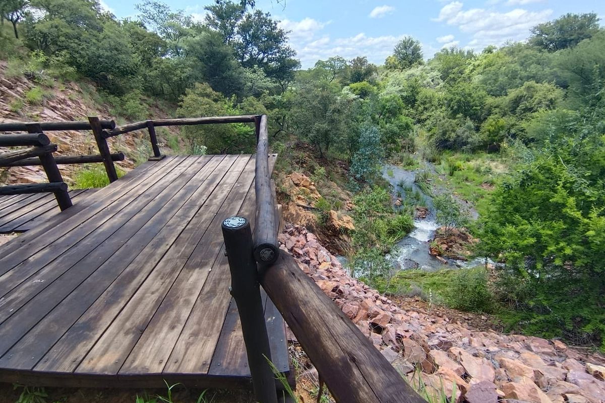 A scenic timber viewing deck overlooking a natural stream and lush, wooded landscape.