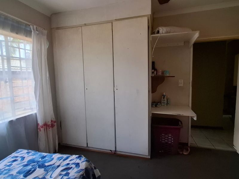 Bedroom featuring built-in cupboards and a small integrated vanity area, requiring cosmetic updates to improve the overall aesthetic and condition.