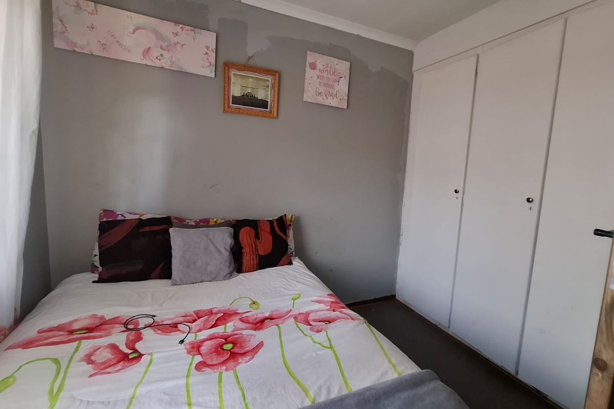 A bedroom featuring built-in cupboards and coving, currently showing signs of wear on the wall surfaces.