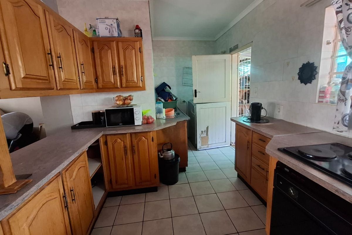 A functional kitchen featuring wooden cabinetry, tiled flooring, and built-in cooking appliances, with a stable door leading to the exterior.