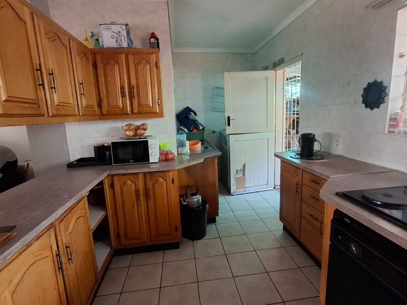 A functional kitchen featuring wooden cabinetry, tiled flooring, and built-in cooking appliances, with a stable door leading to the exterior.