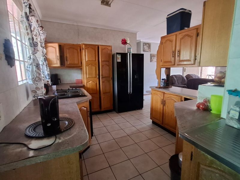 A functional kitchen featuring traditional wooden cabinetry, laminate countertops, tiled flooring, and a built-in hob, offering a practical layout for daily meal preparation.