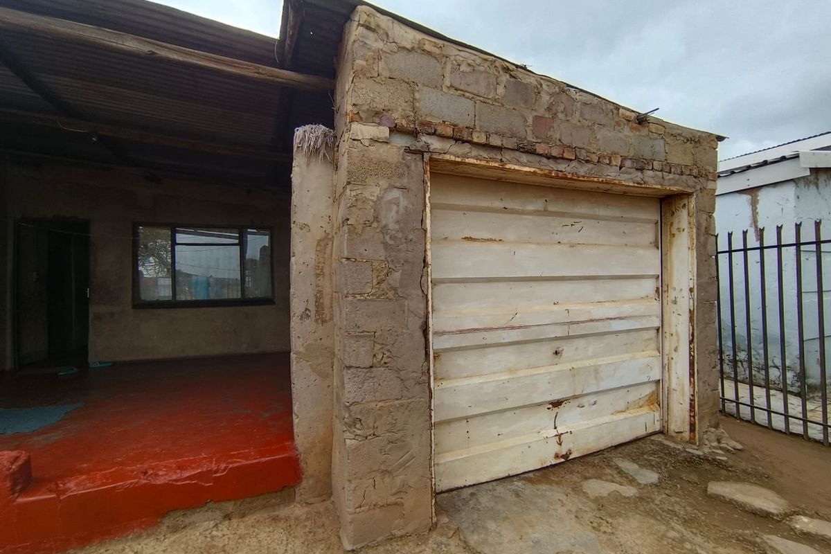 Front exterior view of a property featuring a garage with a metal door and an adjacent covered entrance area with painted concrete flooring.