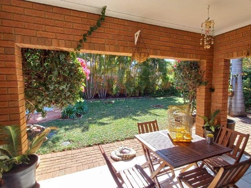 A covered brick patio overlooking a private garden, featuring sturdy brick pillars and paved flooring, ideal for outdoor relaxation and entertaining.