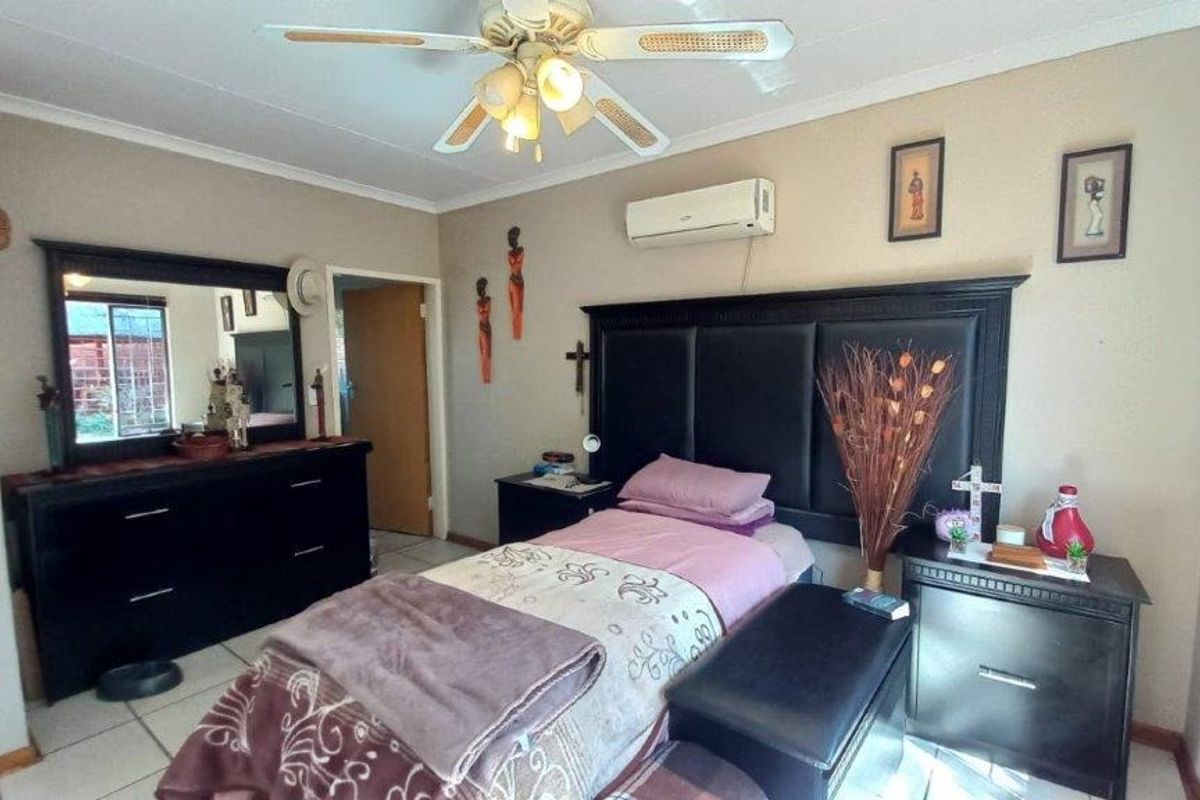 A bedroom featuring tiled flooring, a ceiling fan, and a wall-mounted split-system air conditioner.