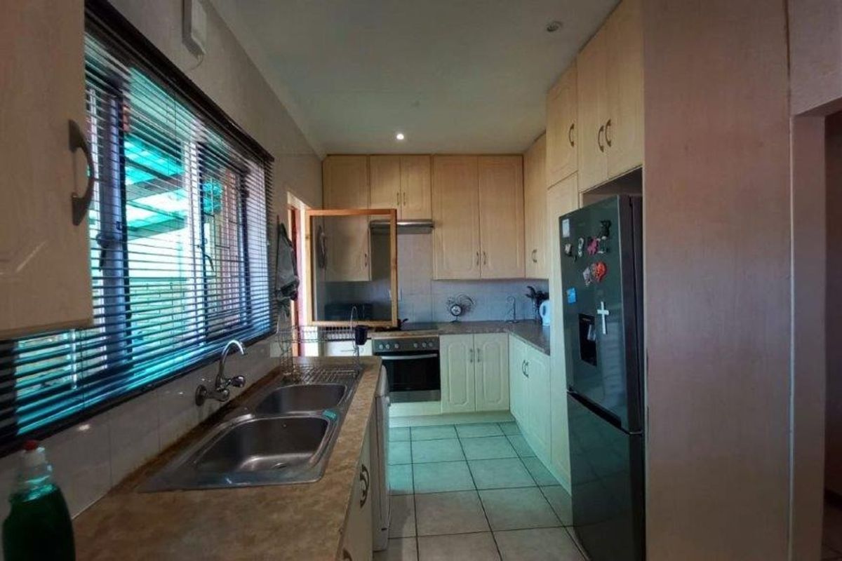 Functional kitchen featuring laminate cabinetry, double bowl stainless steel sink, built-in oven, extractor fan, and tiled flooring.