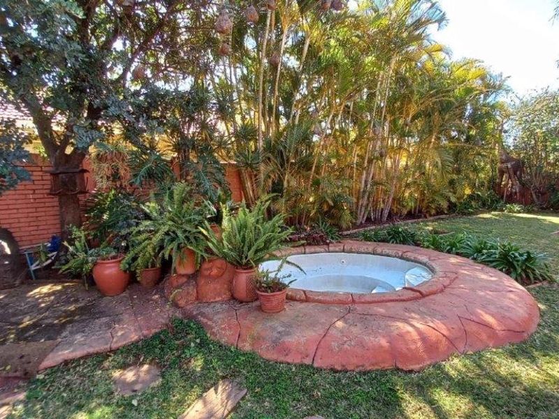 A private garden area featuring a built-in circular spa surrounded by paved landscaping and mature trees.