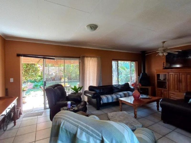 Spacious living room featuring tiled flooring, a freestanding fireplace, and large sliding glass doors providing direct access to the outdoor patio area.