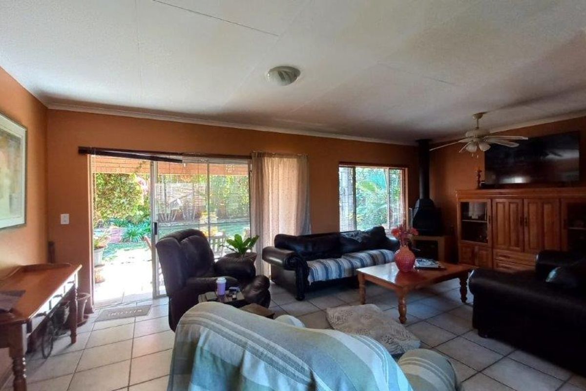 Spacious living room featuring tiled flooring, a freestanding fireplace, and large sliding glass doors providing direct access to the outdoor patio area.