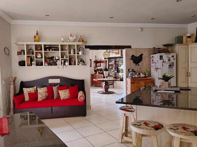 Open plan living and kitchen area featuring a large granite island, tiled flooring, and built-in shelving, creating a functional and connected farmhouse living space.