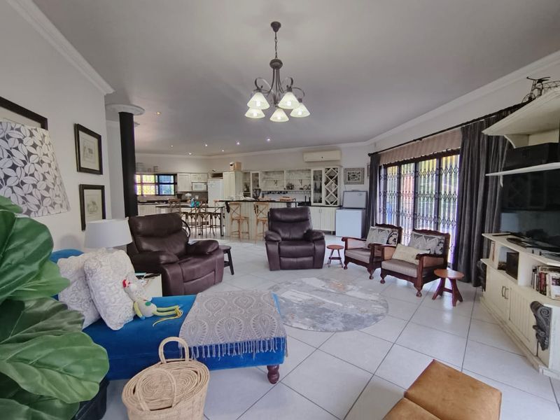 Spacious open-plan living and kitchen area featuring tiled floors, a central island, and large sliding doors leading to the exterior.