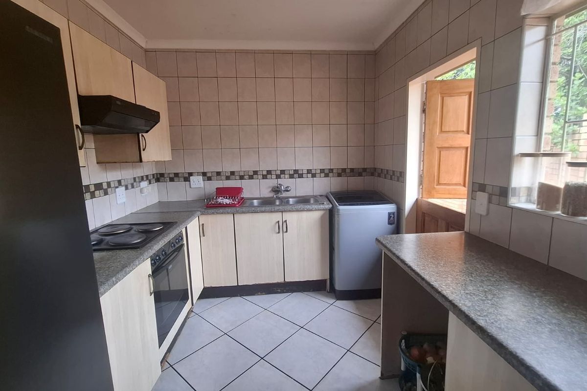 Functional kitchen featuring built-in cabinetry, laminate countertops, electric hob, oven, and tiled finishes with direct access to the exterior.