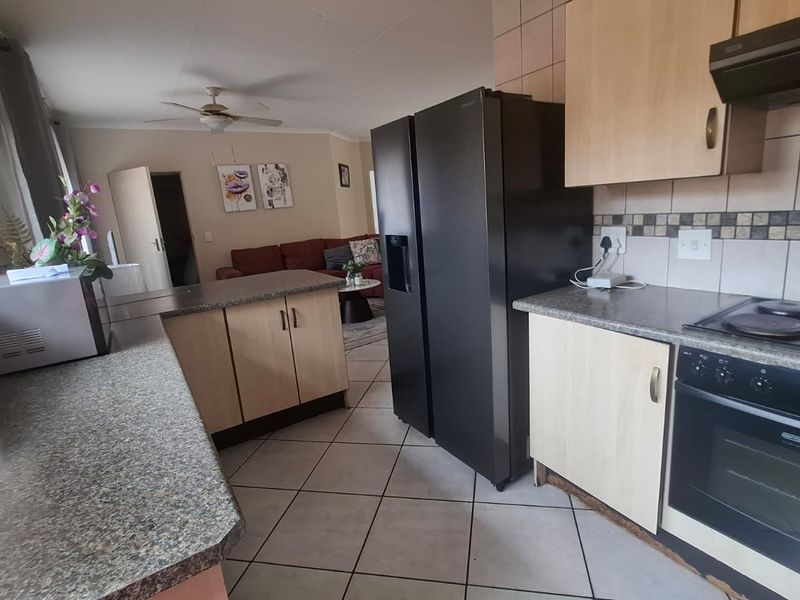 Open-plan kitchen and living area featuring tiled flooring, built-in cabinetry, and integrated cooking appliances, offering a functional layout for daily living.