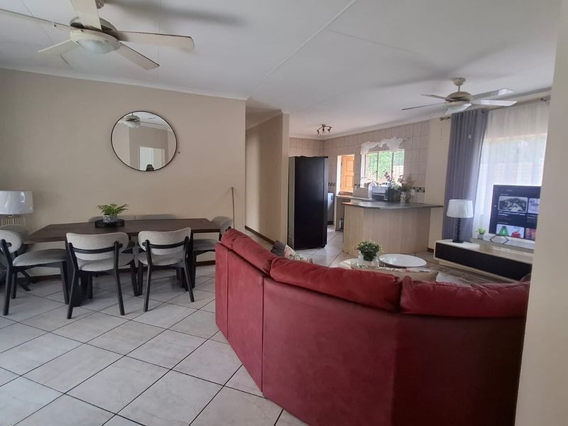 Open-plan living and dining area featuring tiled flooring, ceiling fans, and a functional kitchen with island and cabinetry.