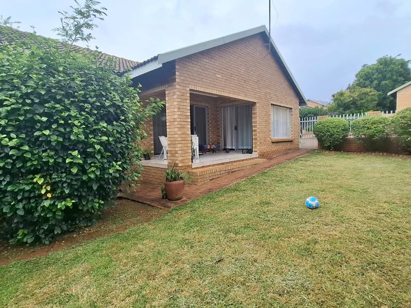Rear view of the house featuring a brick facade, a covered patio area with sliding glass doors, and a private garden with a boundary wall.