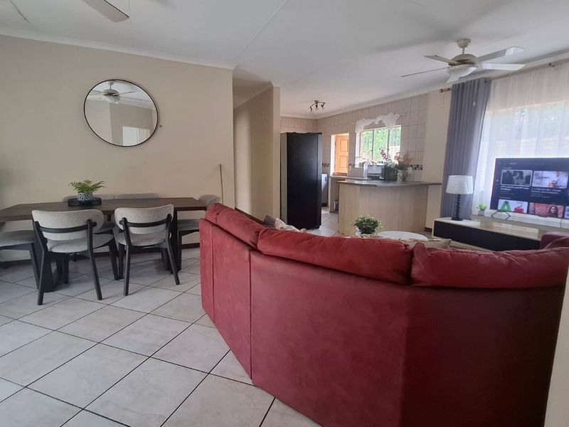Spacious open-plan living and dining area featuring tiled flooring, ceiling fans, and a functional kitchen with a central island.
