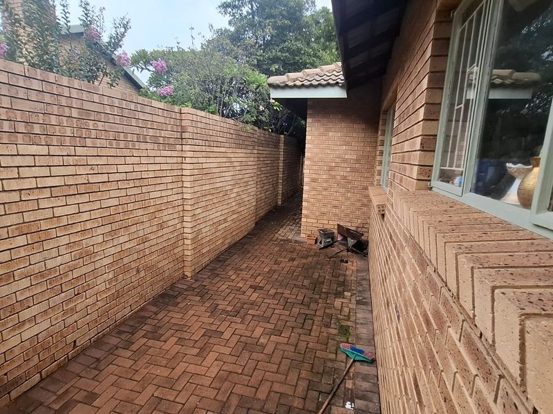 A side passage featuring face brick walls and a paved walkway, providing access along the exterior of the property.