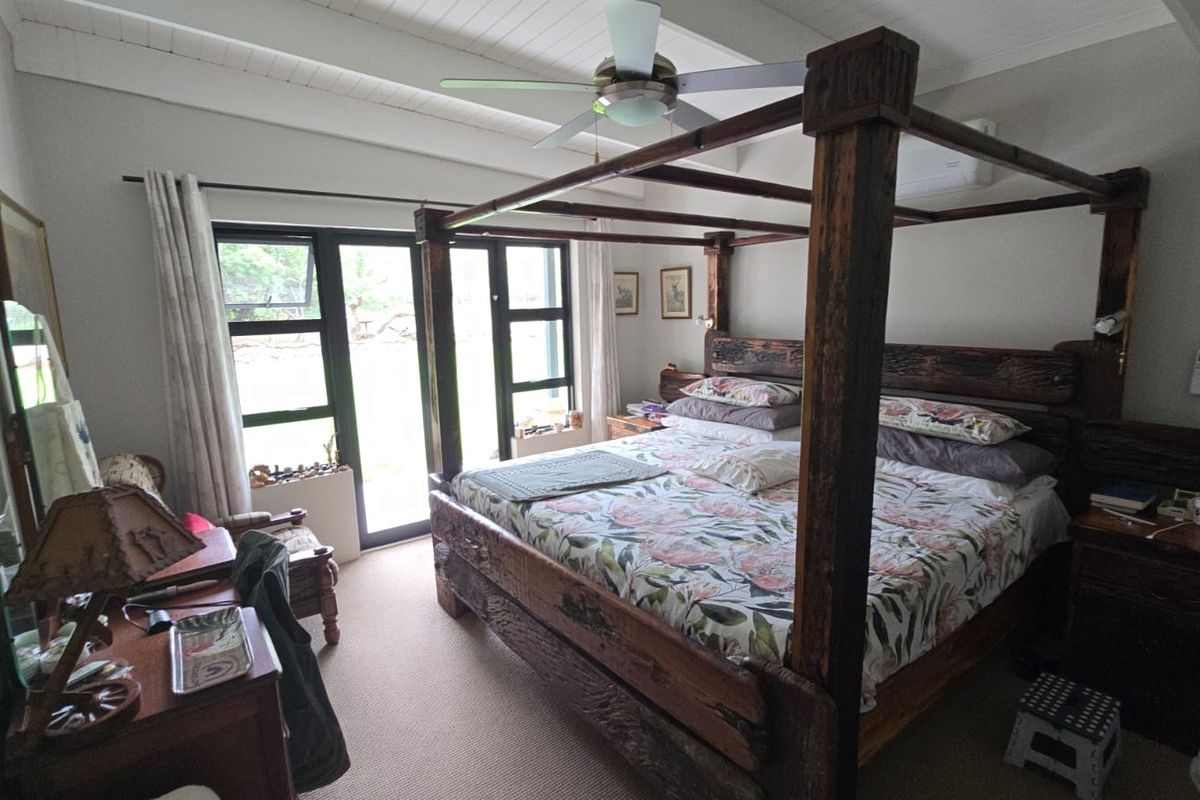 Spacious bedroom featuring exposed beam ceilings, a ceiling fan, air conditioning, and direct access to the garden through sliding glass doors.