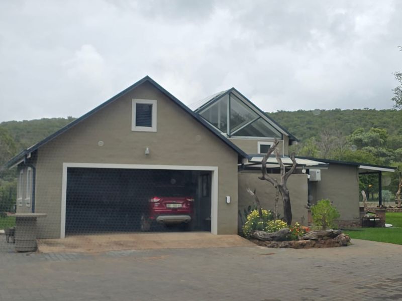 Front view of a residential property featuring a double garage, paved driveway, and a distinctive pitched roof with a large skylight.