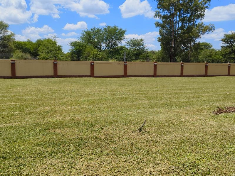 A well-maintained, level residential plot featuring a secure perimeter wall with integrated electric fencing and exterior lighting.