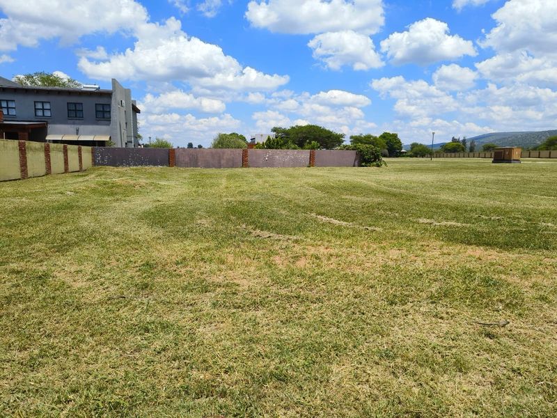 A wide, level residential vacant land plot featuring a mowed lawn and established boundary walls, ready for development.