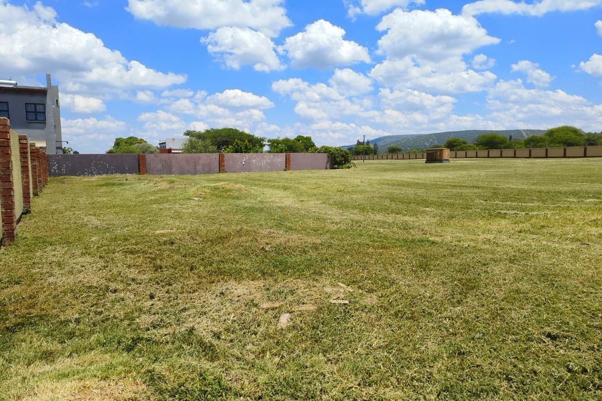 A spacious, level vacant residential plot featuring a well-maintained grass lawn and secure perimeter brick walling.
