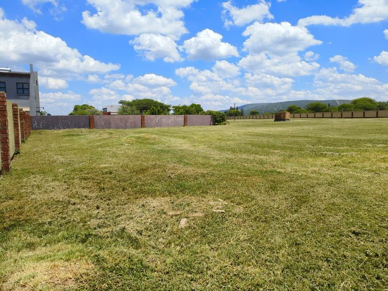 A spacious, level vacant residential plot featuring a well-maintained grass lawn and secure perimeter brick walling.