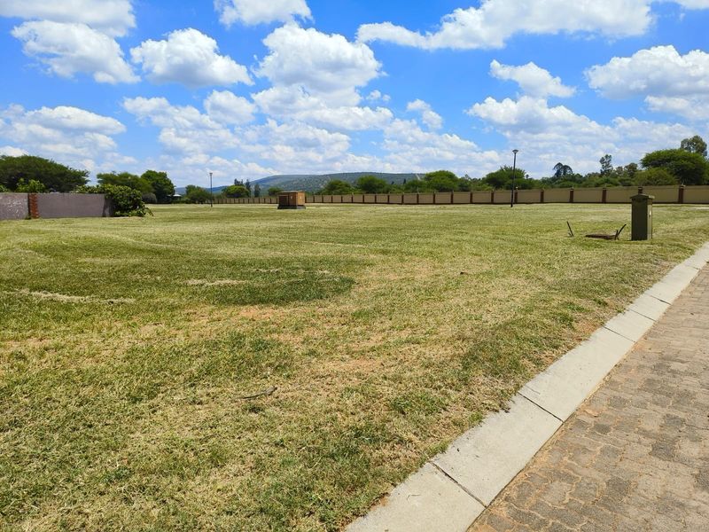 A spacious, level residential vacant stand featuring a well-maintained lawn, perimeter walling, and paved curbing, ready for development.