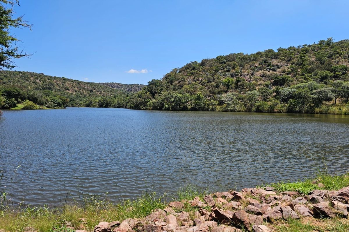 A scenic view of a tranquil lake surrounded by natural hills and lush vegetation, showcasing the peaceful landscape of the property.