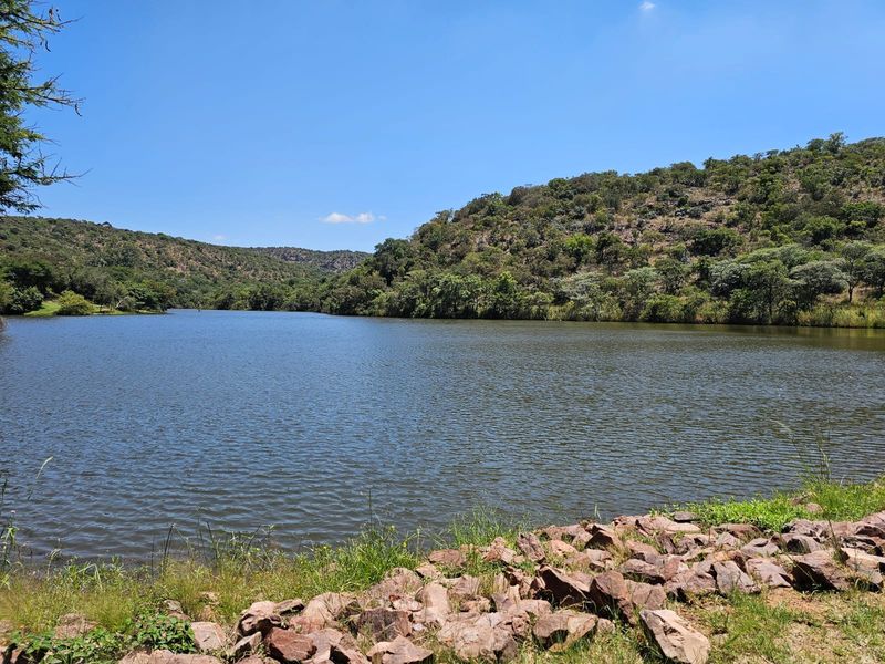 A scenic view of a tranquil lake surrounded by natural hills and lush vegetation, showcasing the peaceful landscape of the property.