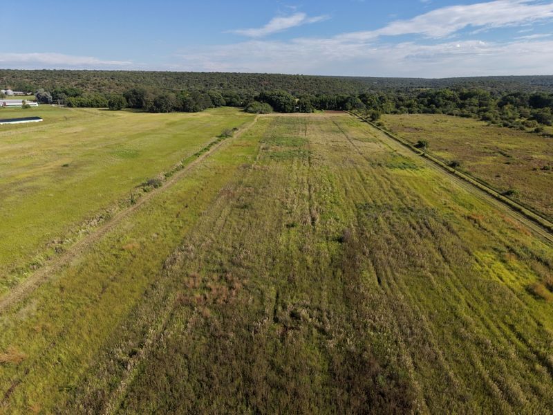 An aerial view of the expansive farm property, showcasing open grazing land, natural vegetation, and surrounding rural landscape.