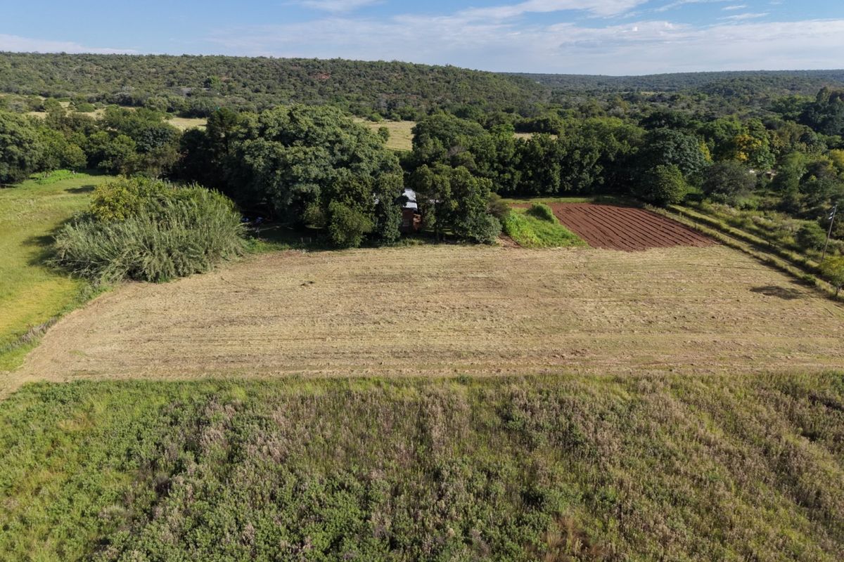 An aerial view of the farm property, showcasing expansive open fields, cultivated land, and established natural vegetation.