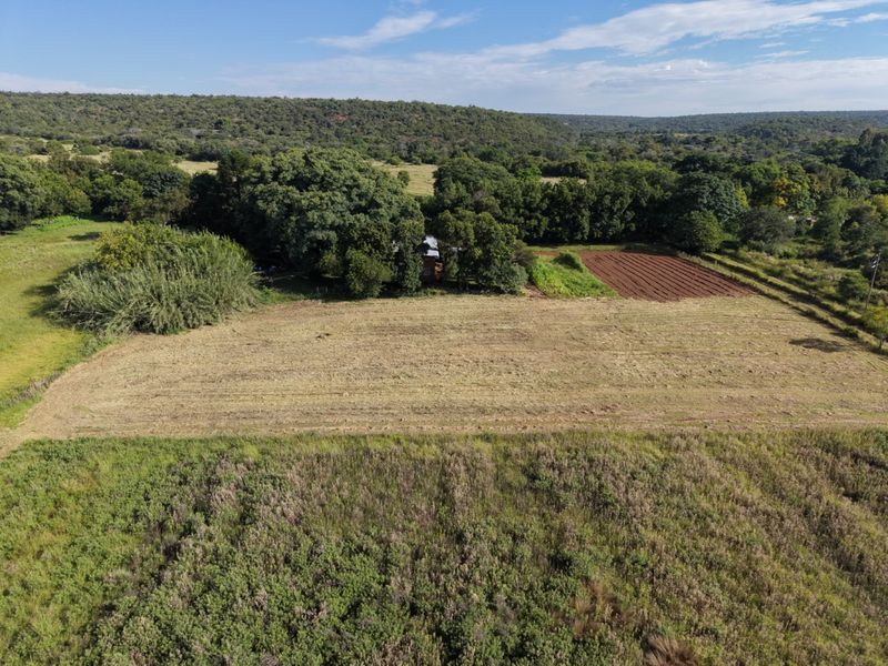 An aerial view of the farm property, showcasing expansive open fields, cultivated land, and established natural vegetation.