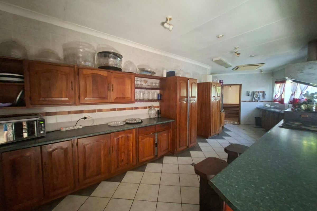 Spacious kitchen featuring extensive wooden cabinetry, laminate countertops, and tiled flooring, offering a functional layout with potential for modern updates.