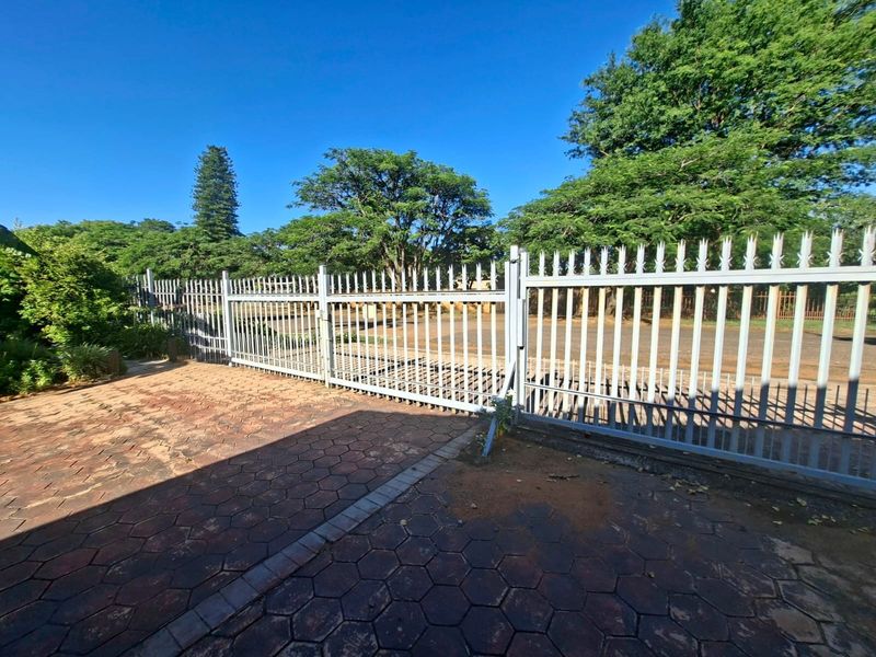 A view of the property entrance featuring a metal security gate and paved driveway area.