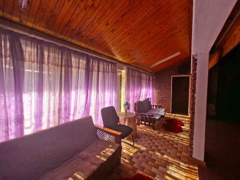 Enclosed patio area featuring a timber ceiling, exposed brick wall, and tiled flooring, offering a rustic space for relaxation.