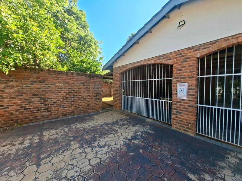 A secure garage area featuring brick construction, metal security gates, and a paved driveway, providing functional vehicle storage and access.
