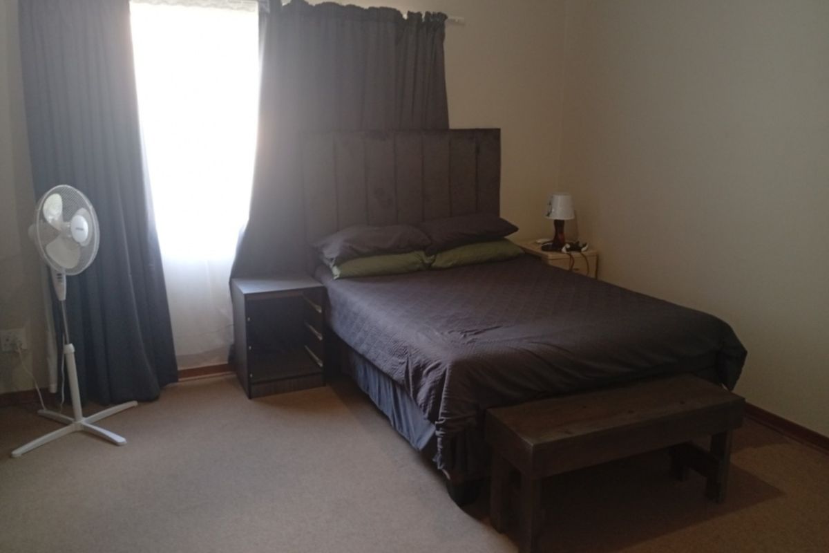 A standard bedroom featuring carpeted flooring and window curtain rails, providing a functional and neutral living space.