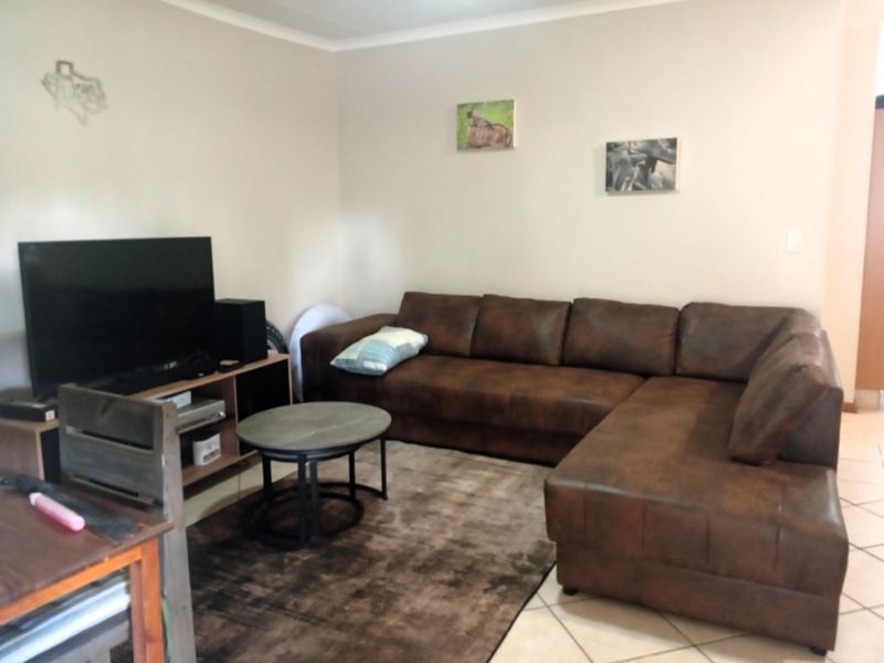 A comfortable living room featuring tiled flooring and neutral wall finishes, providing a functional space for relaxation.
