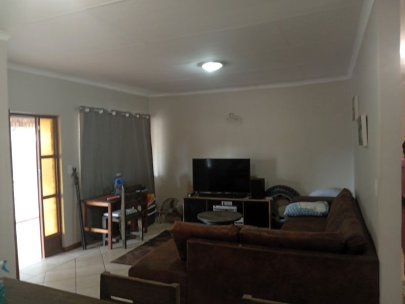 A living room area featuring tiled flooring and a glass panel door leading to an outdoor space.