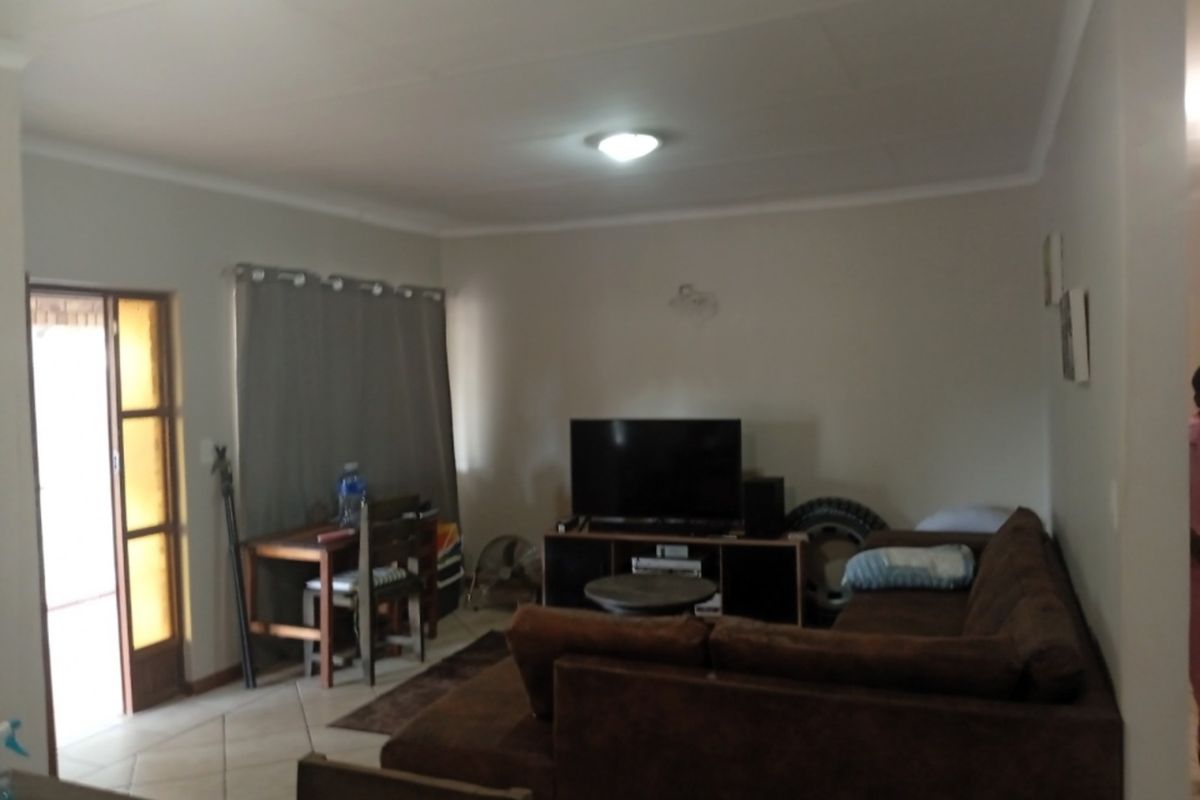 A living room area featuring tiled flooring and a glass panel door leading to an outdoor space.