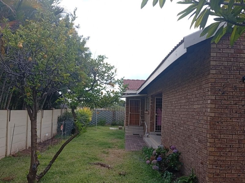 Rear view of the townhouse featuring a face brick facade, tiled roof, and a private garden area with a paved walkway.