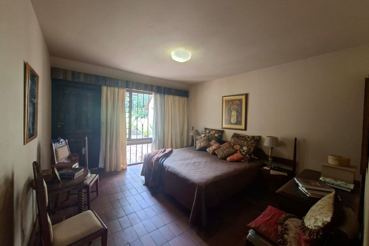 A bedroom featuring tiled flooring and a sliding door with an integrated security gate, providing access to the exterior.
