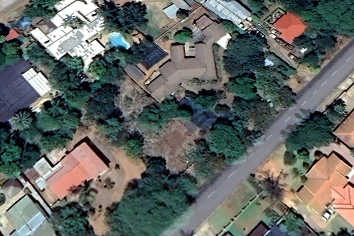 Aerial view of a vacant residential plot featuring mature trees and vegetation, outlined in red within an established suburban neighborhood.