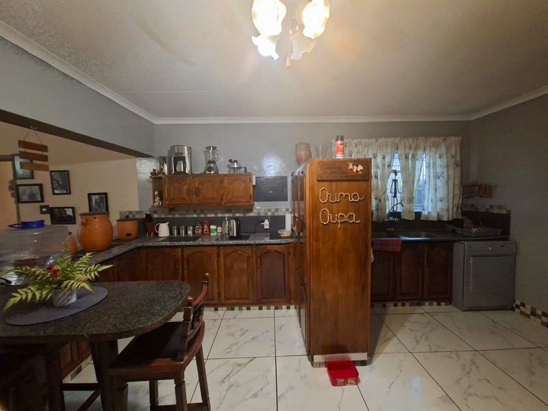 A functional kitchen featuring traditional wooden cabinetry, granite countertops, and tiled flooring, offering a classic layout with ample storage and workspace.